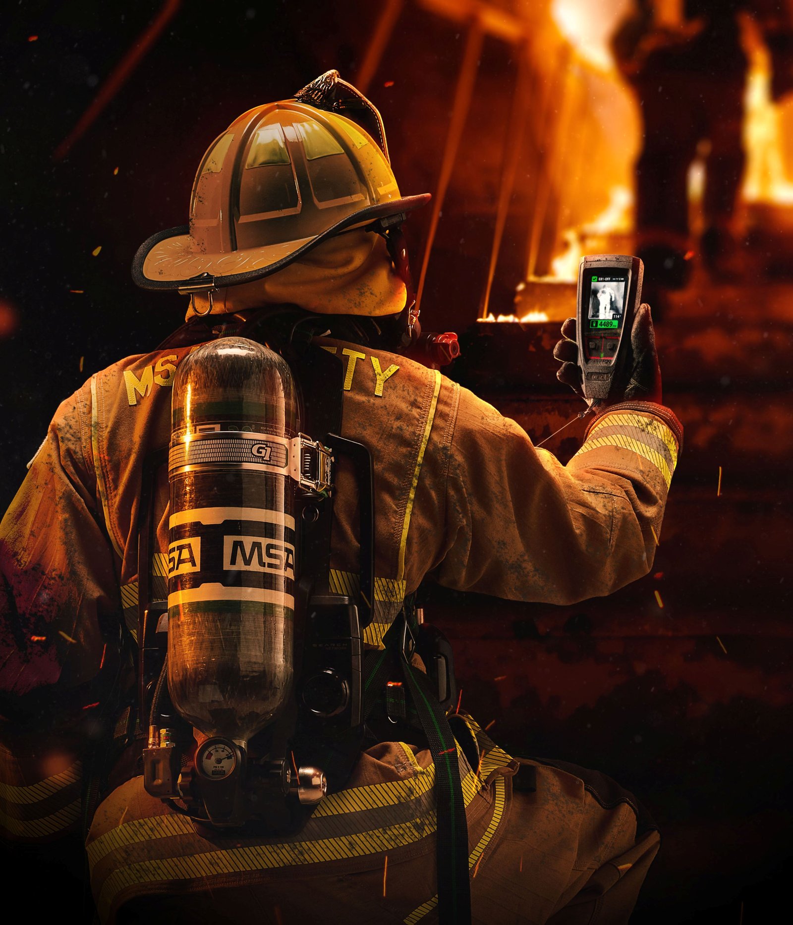 A firefighter seen from behind wearing an MSA breathing apparatus and air cylinder, holding a handheld LUNAR device with a thermal display toward a fire