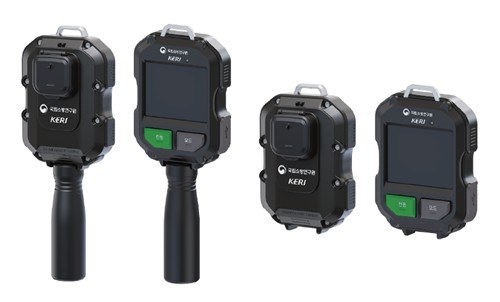 Product rendering of the National Fire Research Institute and KERI visual-enhancement thermal camera: a black rectangular handheld unit with a lens on the front and a screen with green and gray buttons on the back, shown with and without its detachable pistol grip